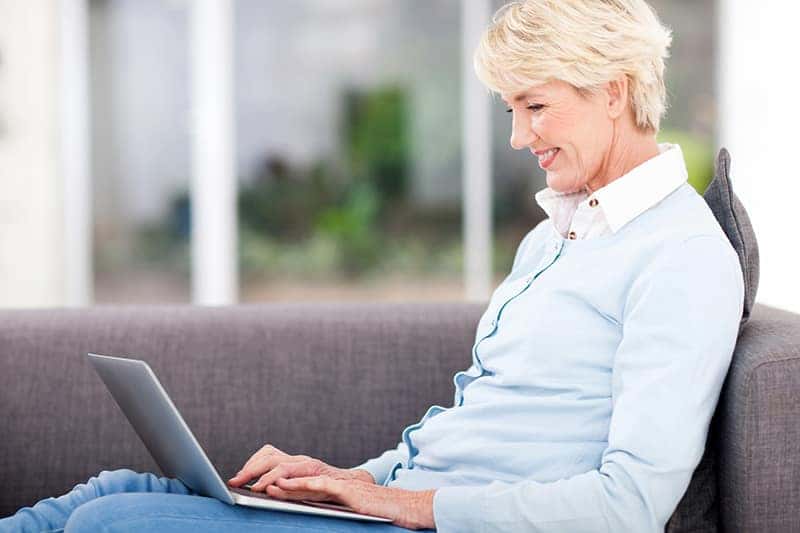 happy elderly woman using laptop computer at home