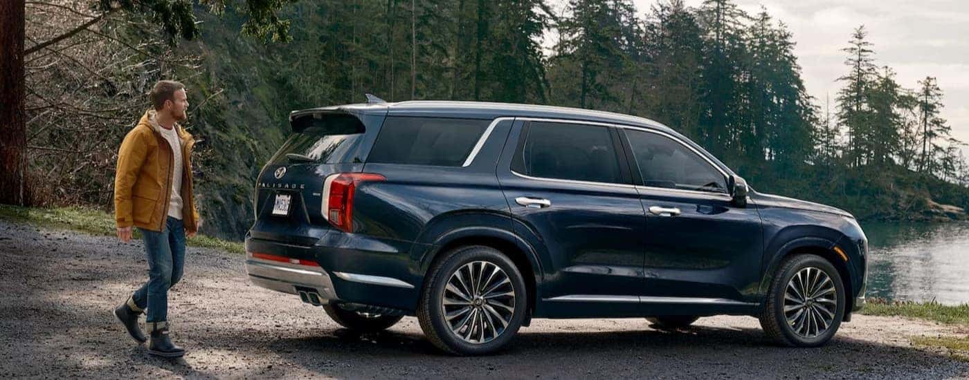 A blue 2025 Hyundai Palisade is shown parked near a lake.