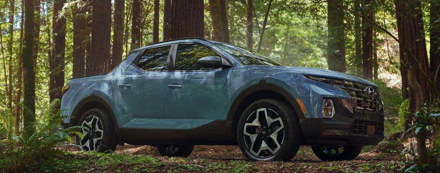 A blue 2022 Hyundai Santa Cruz driving in the woods.