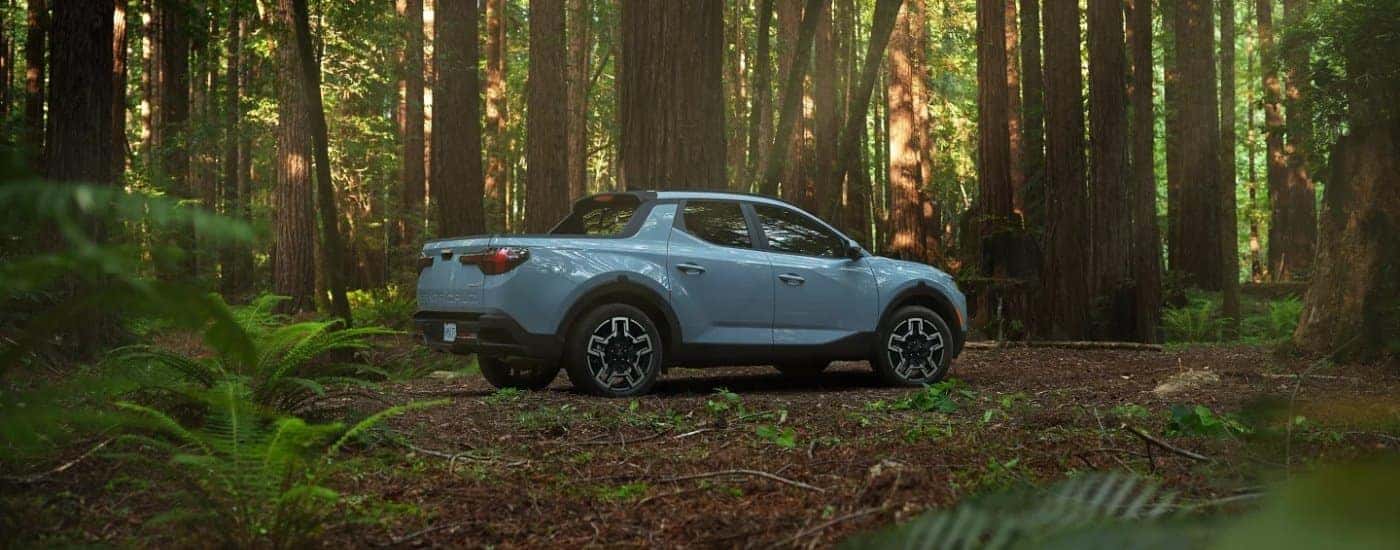A blue 2025 Hyundai Santa Cruz from the side in a forest.