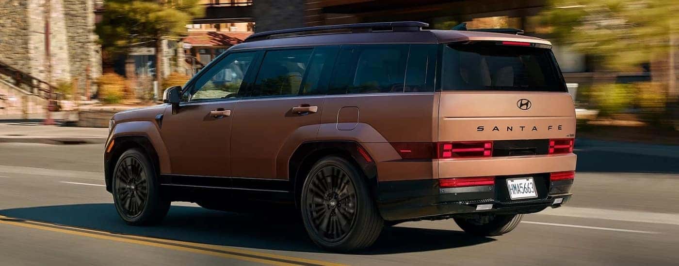 A bronze 2025 Hyundai Santa Fe from the rear.
