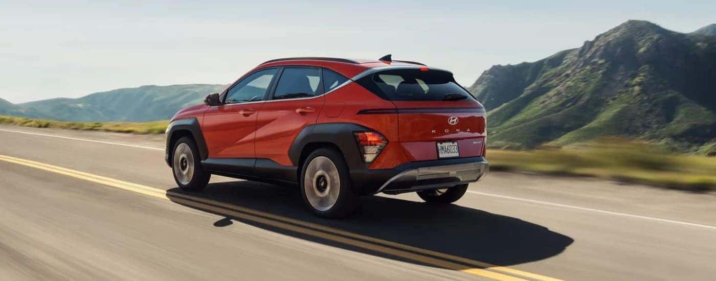 A red 2024 Hyundai Kona Limited driving on a highway