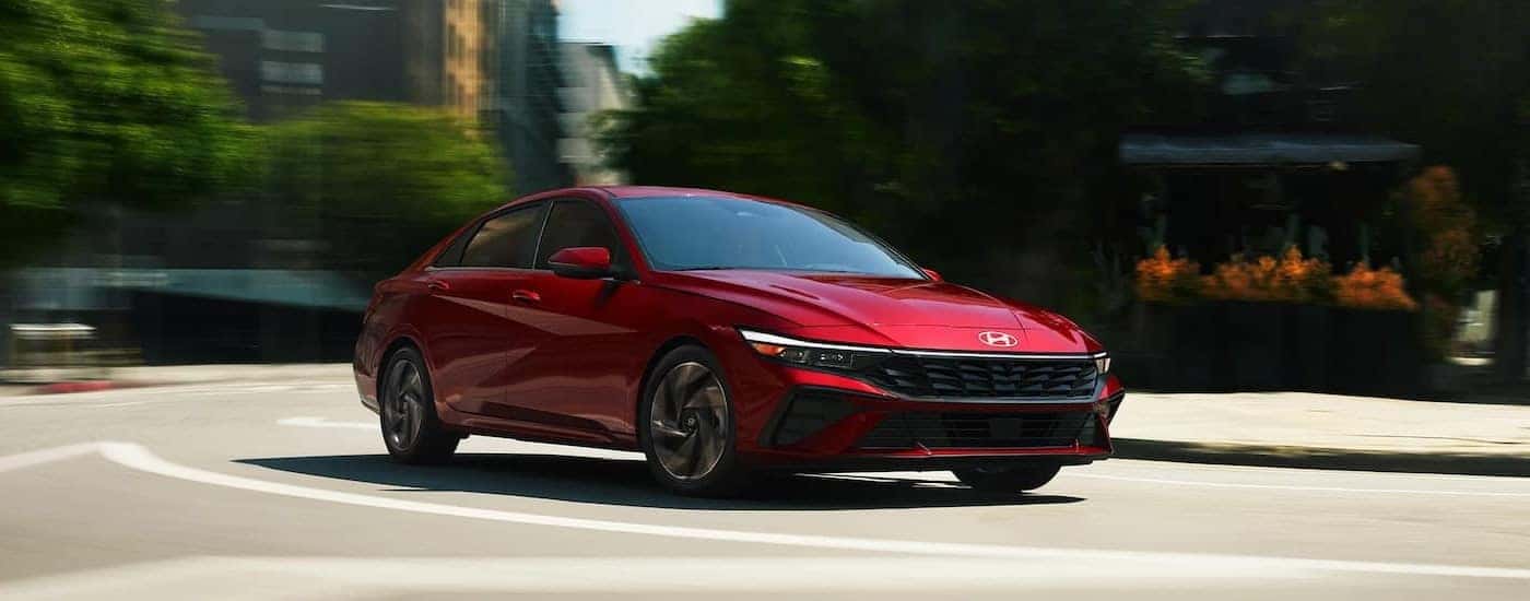 Red 2024 Hyundai Elantra for sale driving around a bend.