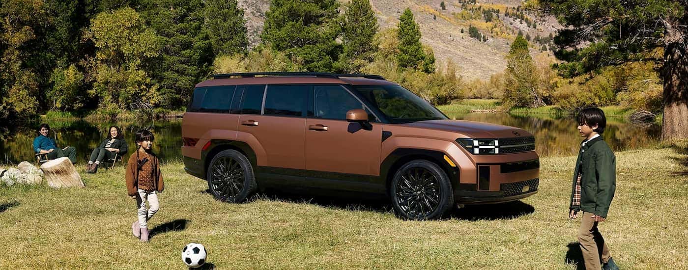 A copper 2024 Hyundai Santa Fe is shown parked near kids playing soccer.