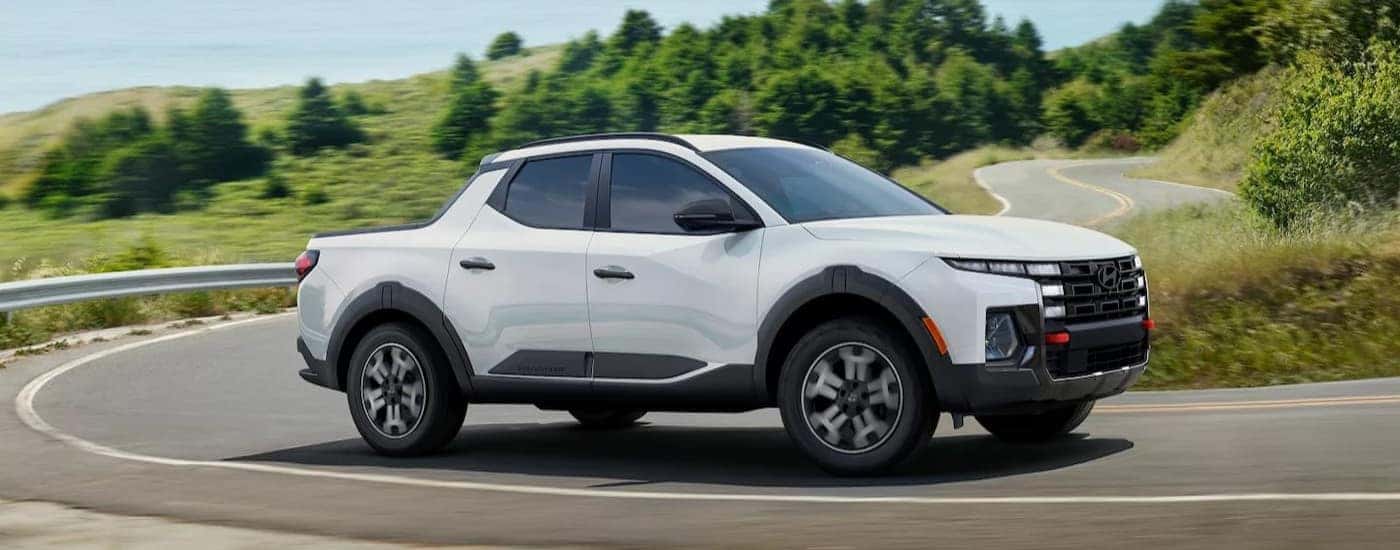 A white 2025 Hyundai Santa Cruz for sale driving on a highway.