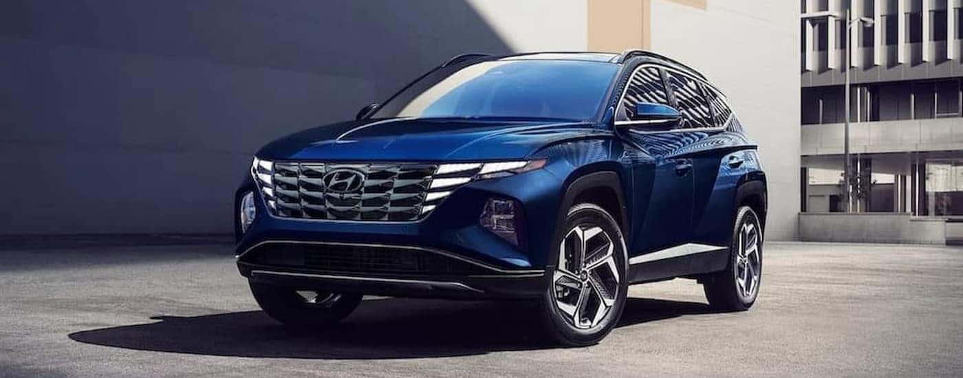 A blue 2023 Hyundai Tucson parked in a city.