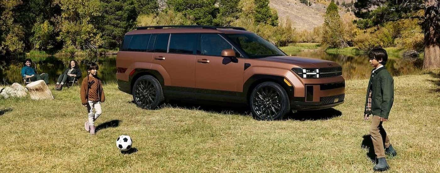 A copper 2024 Hyundai Santa Fe parked near a family.