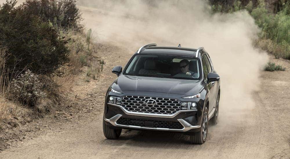 A gray 2022 Hyundai Santa Fe driving on a dirt road.