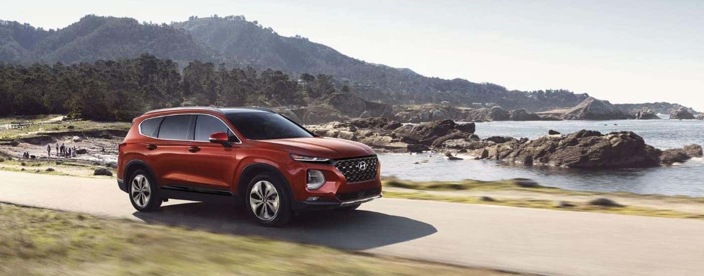 A red 2019 Hyundai Santa Fe driving near a lake