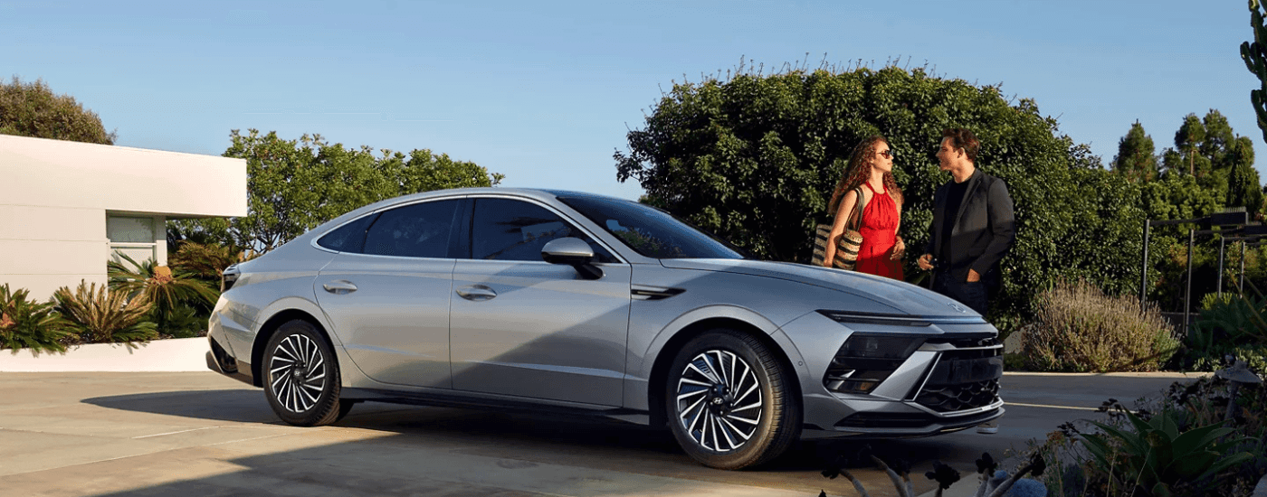 A couple standing next to a silver 2026 Hyundai Sonata