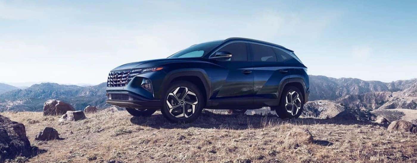 A blue 2023 Hyundai Tucson parked off-road near mountains