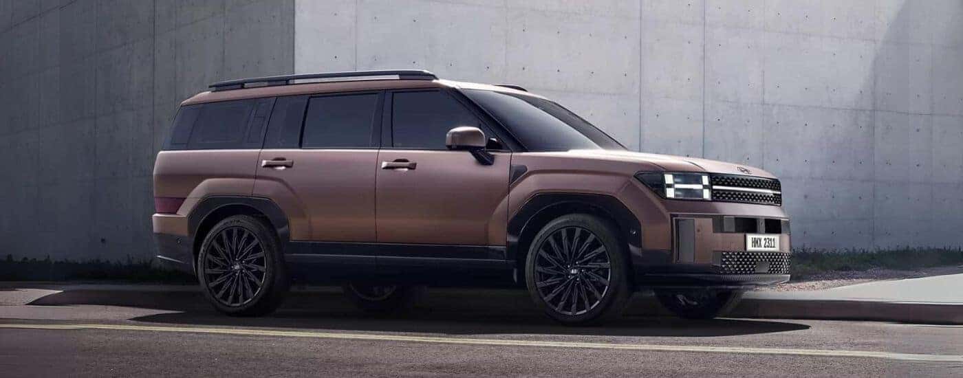 A brown 2024 Hyundai Santa Fe parked by a concrete building.