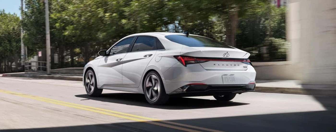A white 2021 Hyundai Elantra driving in a city.