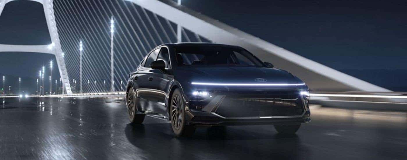A black 2026 Hyundai Sonata driving over a bridge on a rainy night.