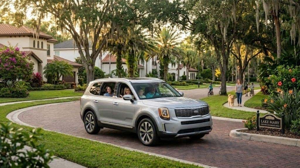 Drive a Kia in Lake Mary & Sanford A silver Kia Telluride SUV driving through a premium residential neighborhood typical of Lake Mary or Longwood, Florida.