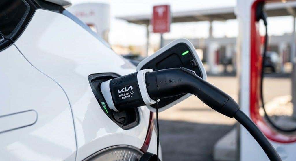 Close-up of a Kia NACS-to-CCS adapter connecting a Tesla Supercharger cable to a Kia EV6 charging port.
