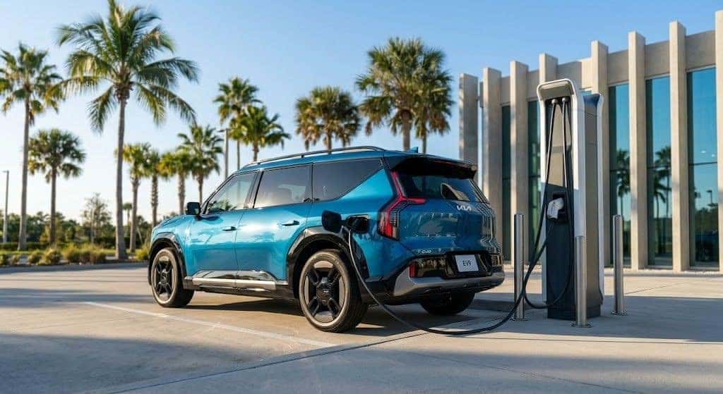 2026 Kia EV9 in Ocean Blue charging at a high-speed OUC ReCharge station in a sunny Orlando setting with palm trees.