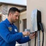 a certified electrician installing a sleek, residential Level 2 EV charging station on the side of a modern Orlando suburban home