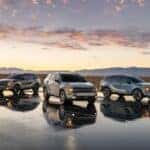Three 2026 Kia Sportage models parked on a reflective surface during a desert sunset.