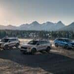 Three 2026 Kia Sorento models in different colors parked in a misty mountain valley at sunrise.
