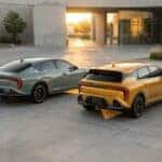 Rear angle comparison of the 2026 Kia K4 Sedan in green and the K4 Hatchback in gold at sunset.