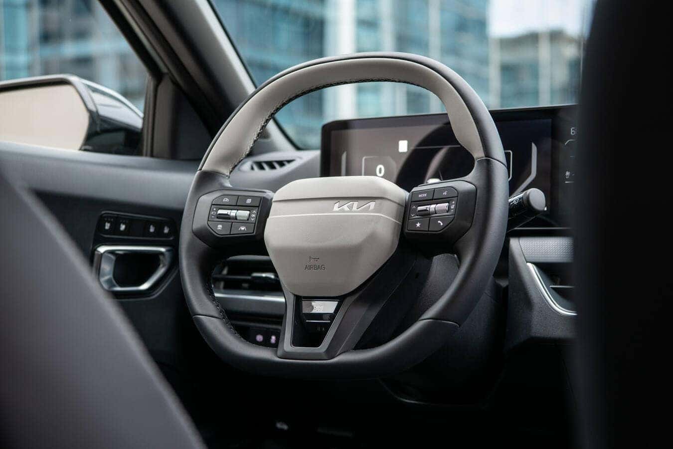 The sporty 3-spoke sport steering wheel and dashboard controls of the 2026 Kia K4 GT-Line
