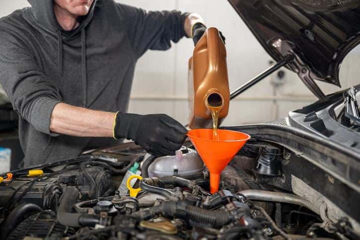 A certified technician performing an oil change on a vehicle