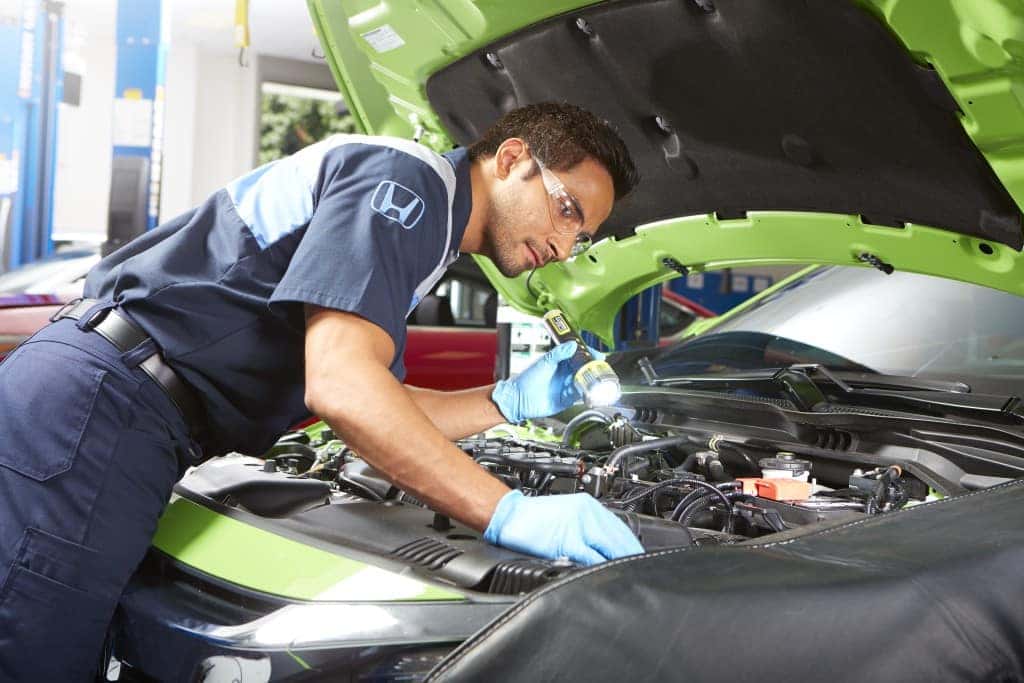 Changing your transmission fluid at Jim Coleman Auto Group of Maryland | Honda technician checking car engine