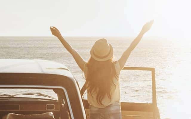 woman steps out of car with arms outstretched