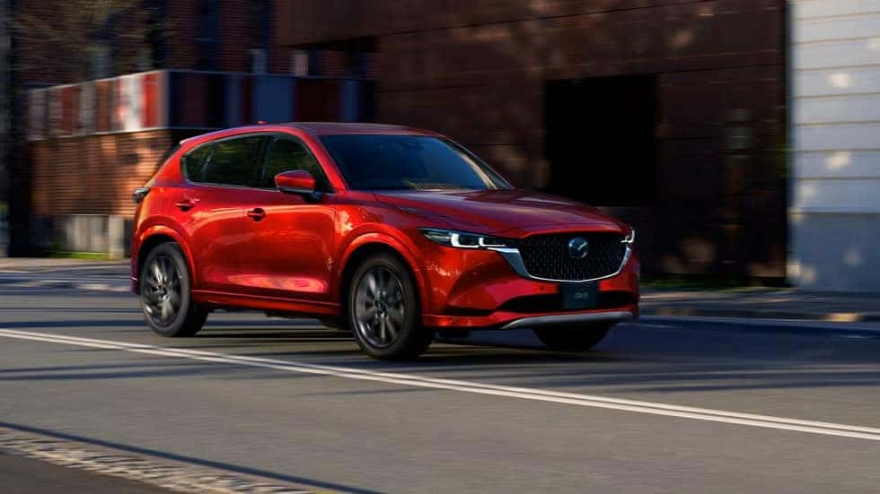 A red Mazda hatchback driving on the road