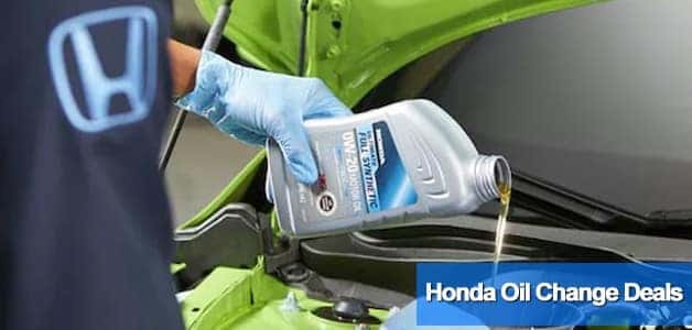 Honda technician changing the oil under the hood of a Honda vehicle