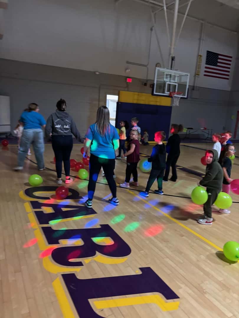 group of children and adults in gym with party lights