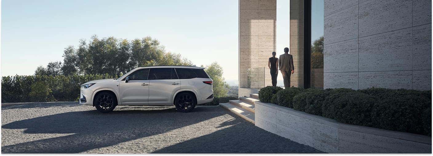 White 2026 Lexus TX SUV parked in profile outside a modern architectural building.