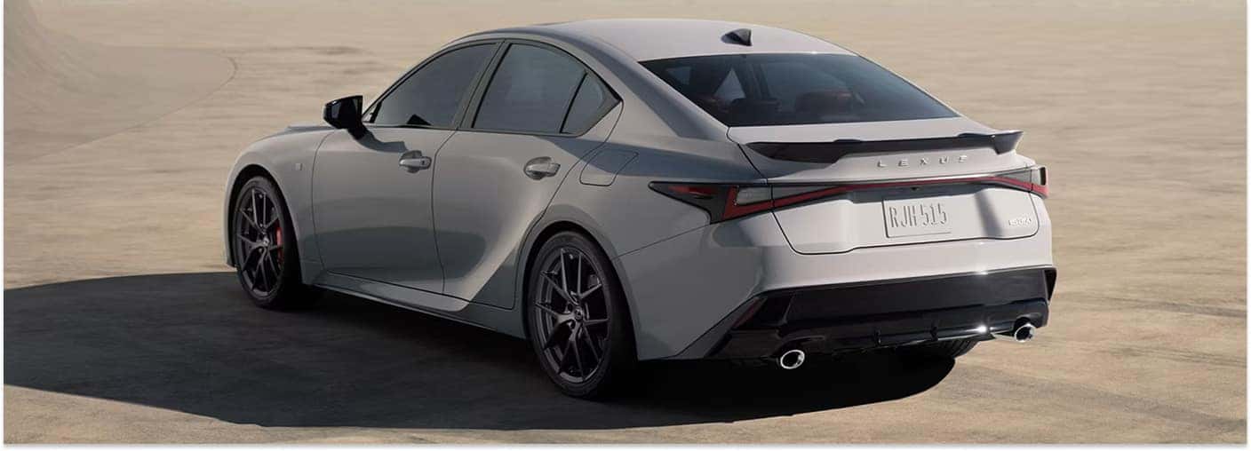 Rear three-quarter view of a grey 2026 Lexus IS sedan parked on a concrete surface.