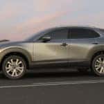 A silver Mazda CX-30 on a paved road at sunset.