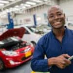 Smiling auto service technician standing in a repair shop