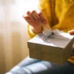 Young woman in yellow sweater opening gift box