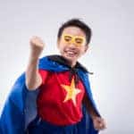 Asian boy wearing a homemade superhero costume with a cape and star logo