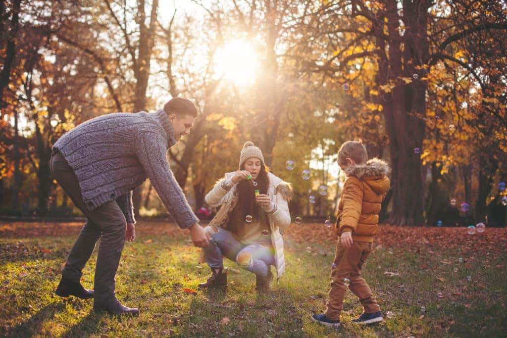 Happy family blowing bubbles at the park