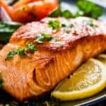Grilled salmon on a plate with lemon slices and green garnish