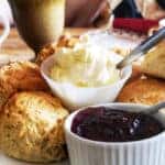 A plate of scones with jars of clotted cream and jam.