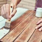 hands painting an old wooden table with a brush