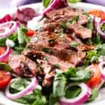 closeup of steak salad with red onions and tomatoes