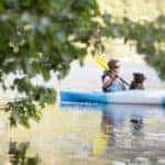 A woman in a blue and white kayak with her dog