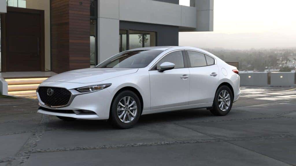 White 2024 Mazda3 parked in front of a modern building