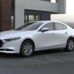 White 2024 Mazda3 parked in front of a modern building