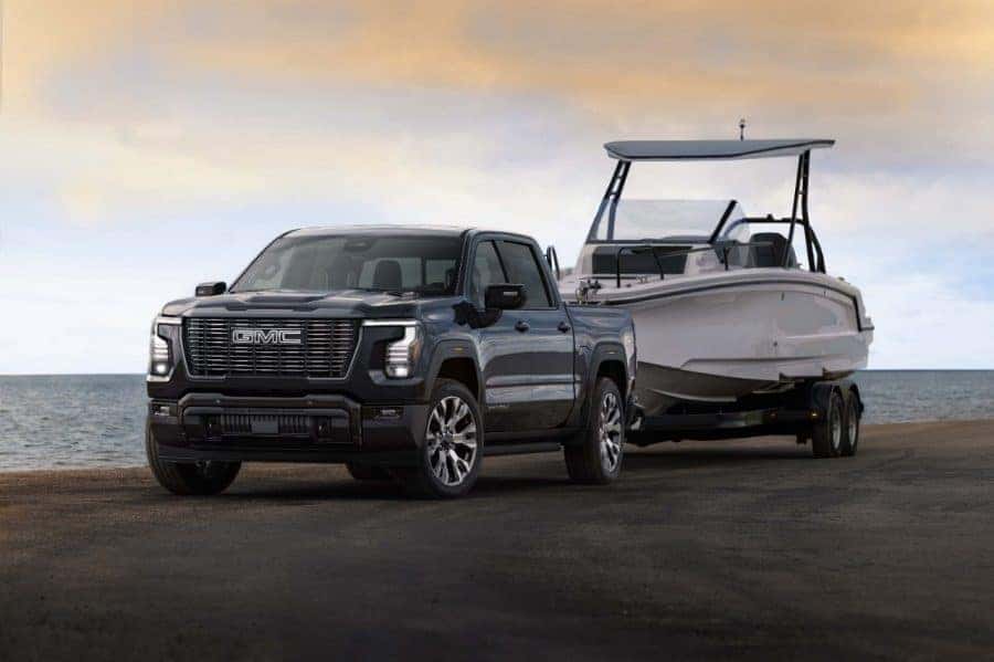 2027 GMC Sierra 1500 Denali Ultimate in Dark Ridge Metallic towing a boat. Exterior 3/4 shot. Preproduction model shown. Actual production model may vary.