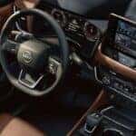 Interior view of the 2025 Nissan Rogue, showing the steering wheel, dashboard, and the infotainment system