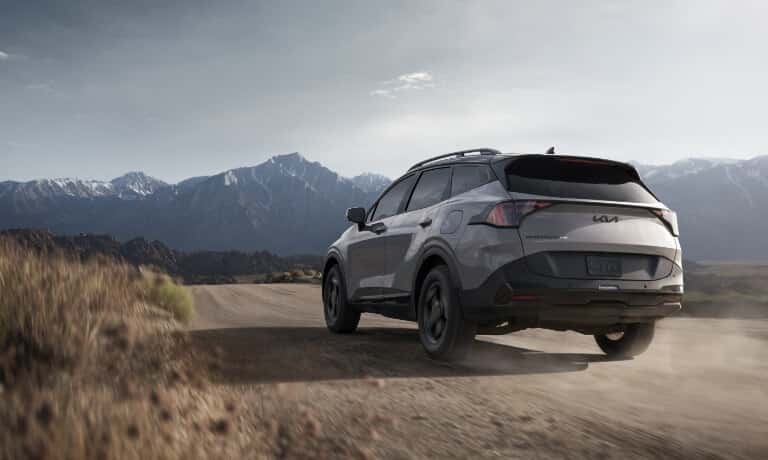 2026 Kia Sportage driving away in mountains