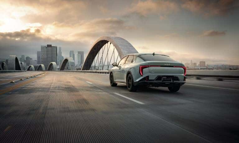 2026 Kia K4 driving on bridge toward city